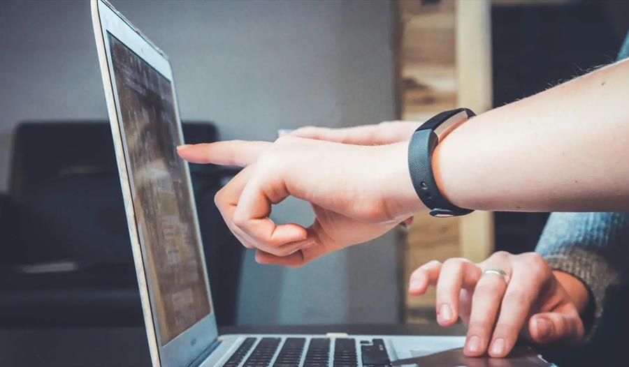 Åpen bærbar PC og fingre som peker mot skjermen