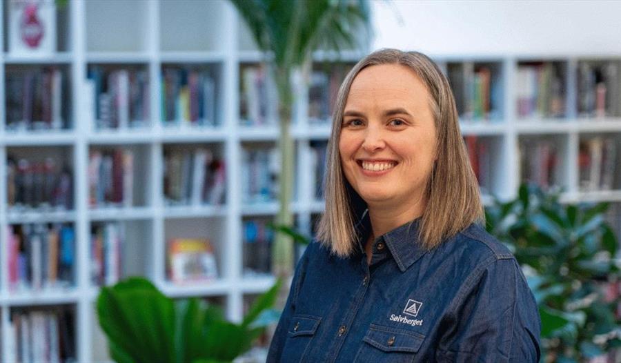 En bibliotekar som står foran bokhyllene