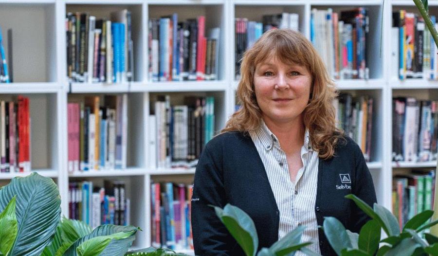 En bibliotekar som står foran bokhyllene