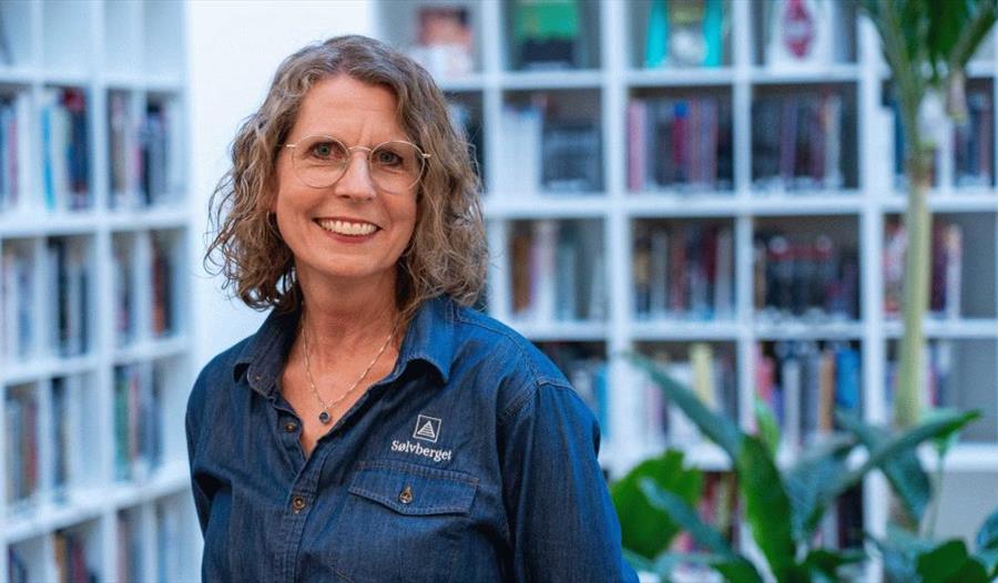 Bibliotekar foran bokhyller fylt med bøker