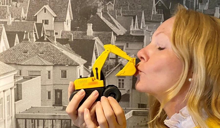 Tove Galta med lekegravemaskin og bildet av gammel Stavanger som bakgrunn