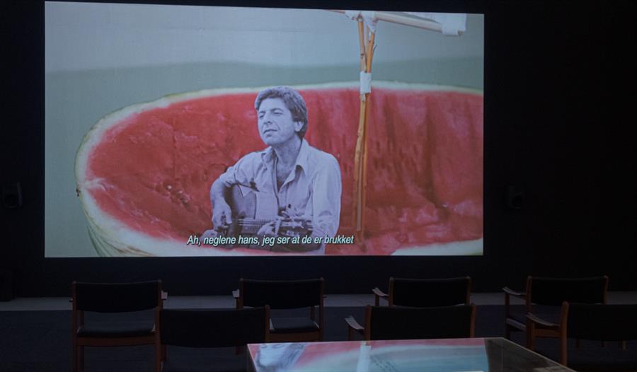 Skjerma med en sanger som spiller gitar og synger