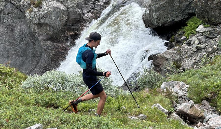 En man på tur i fjellet passerer en foss