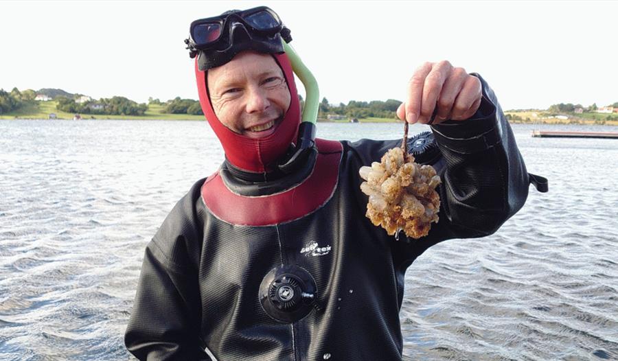 Rudolf Svensen viser frem noe han har funnet i havet etter dykket