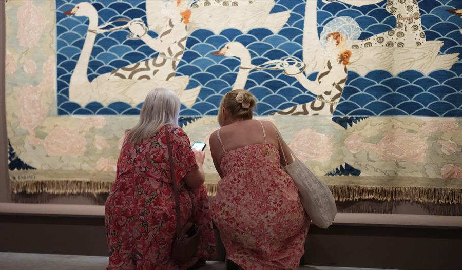 Frida Hansens tekstilkunstverk med svaner og to besøkende