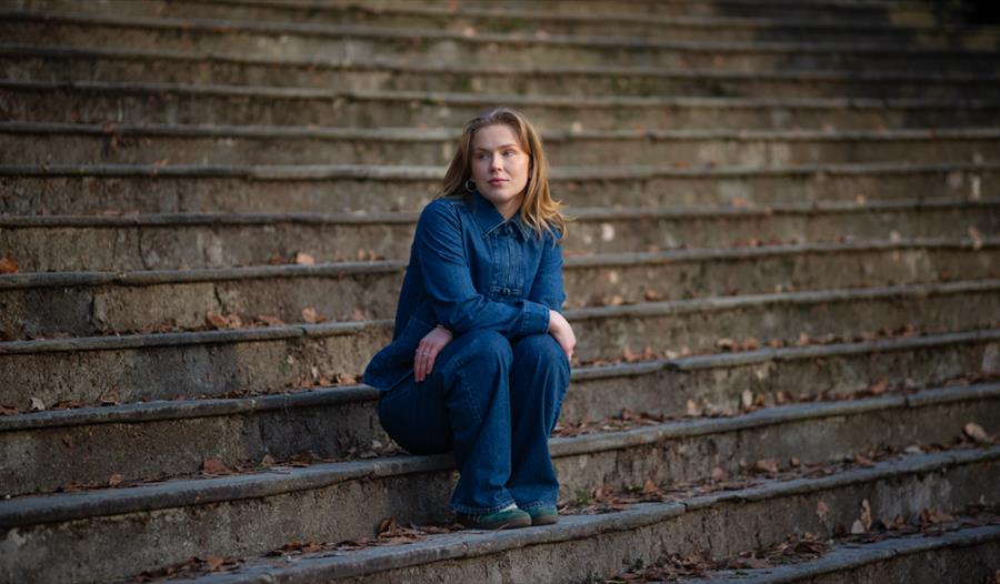 Sigrid Lygren sitter på noen trapper, med falne løv rundt henne.