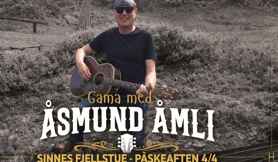 Åsmund Åmli med gitar sitter i naturen
