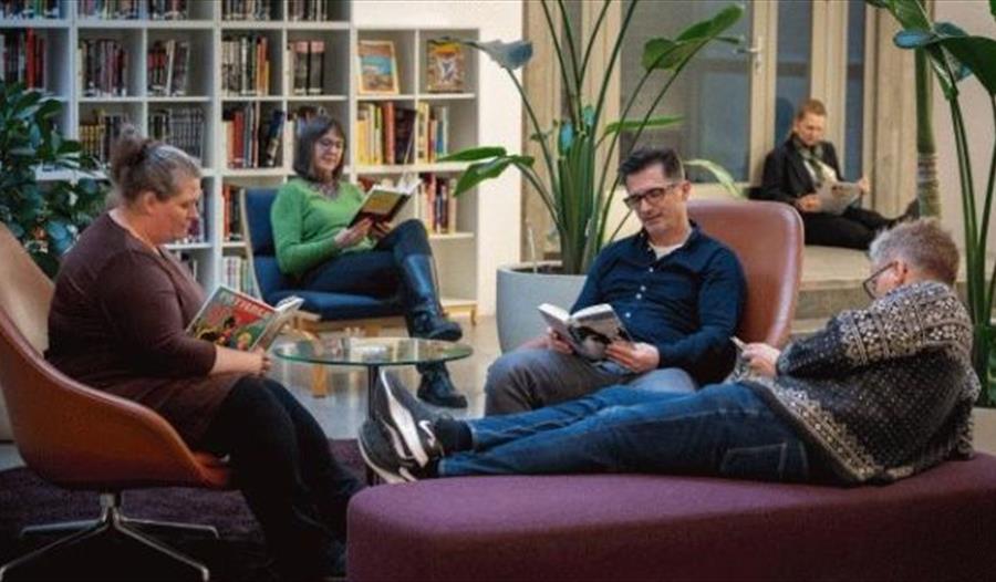 Besøkende sitter i biblioteket og leser
