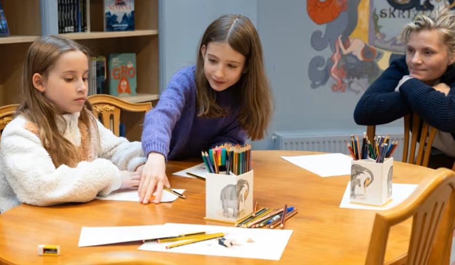 Barn sitter ved et bord og tegner