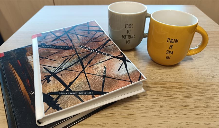 To kopp for kaffe og to bøker på bordet