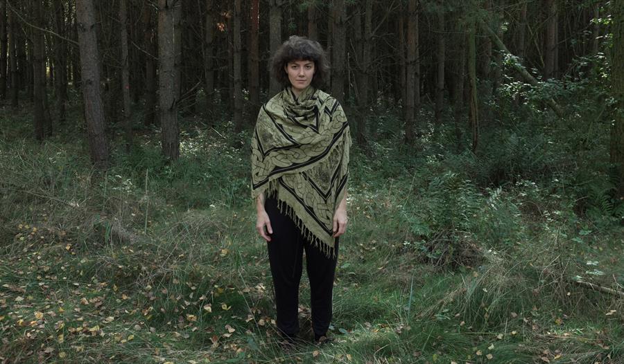 Kaja Draksler som står i utkanten av en skog.