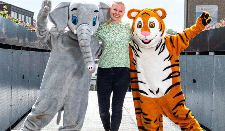 En jente med to artister utkledd som en tiger og en elefant