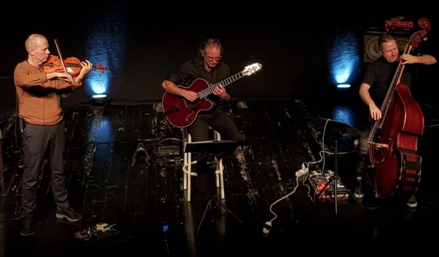Tre musikanter på scenen: Frode Kjekstad - guitar, Per Mathisen - bass, Stig Wigestrand - fiolin