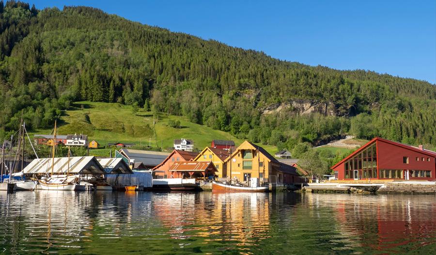 Oversikt over Hardanger Fartøyvernsenter og det nye kulturnaustet med båtar og verkstader ved kaien.