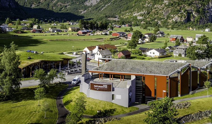 Et dronebilde av Norsk Natursenter med hus og gårder i bakgrunnen.