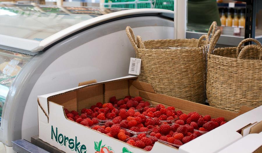 Saftige bringebær i ei kasse merka “Norske Bær”, klare for sal i den sjarmerande gardsbutikken i Øystese.