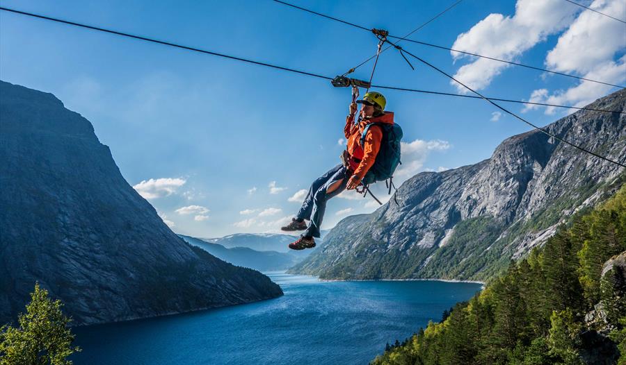 Deltakar på Trolltunga Zipline svevar høgt over fjord og bratte fjell i Hardanger.