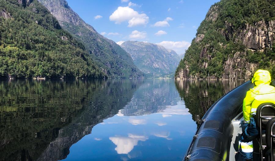 Spegelblank fjord omgitt av majestetiske fjell, sett frå ein RIB-båt på Norheimsund RIB Seafari i Hardanger.