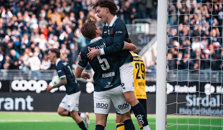 To fotballspillere i Viking FK feirer et mål foran fullsatte tribuner