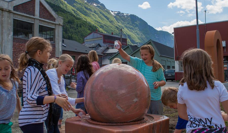 Born leikar ved vassfontena på KraftLaben, omgitt av mektige fjell i Hardanger.