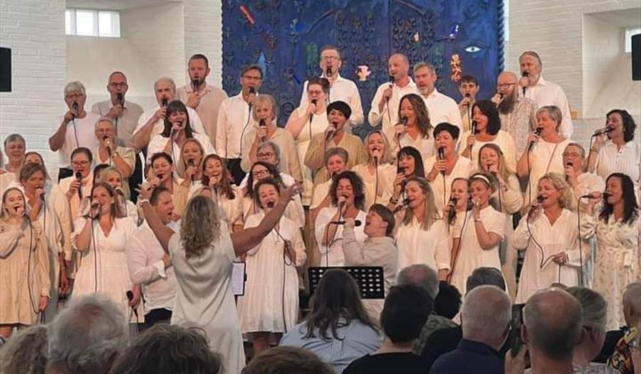 Et hvitkledd gospelkor på en scene