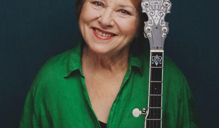 En kvinne, Kari Svendsen, kledd i grønt og med en gitar i hendene.