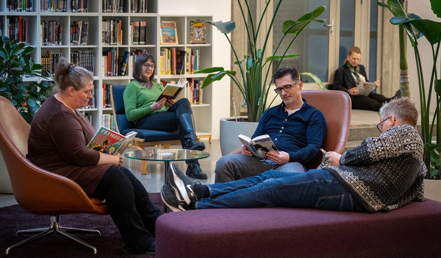 Folk som sitter og leser i biblioteket.