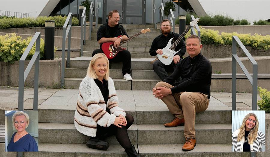 Fire musikere som sitter på en utendørs trapp med hver sitt instrument i hendene.