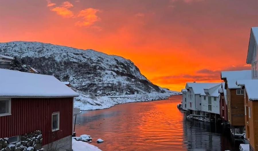 Solnedgangsutsikt med snødekte hus.