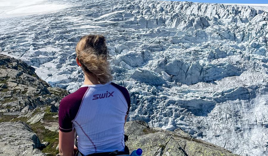 Kvinne sitter og ser utover Buerbreen, en del av Folgefonna.