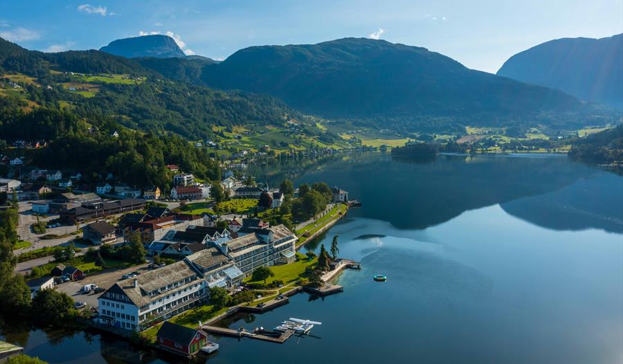 Luftfoto av Brakanes Hotel i Hardanger, med utsikt over fjord, fjell og vakre omgjevnader.