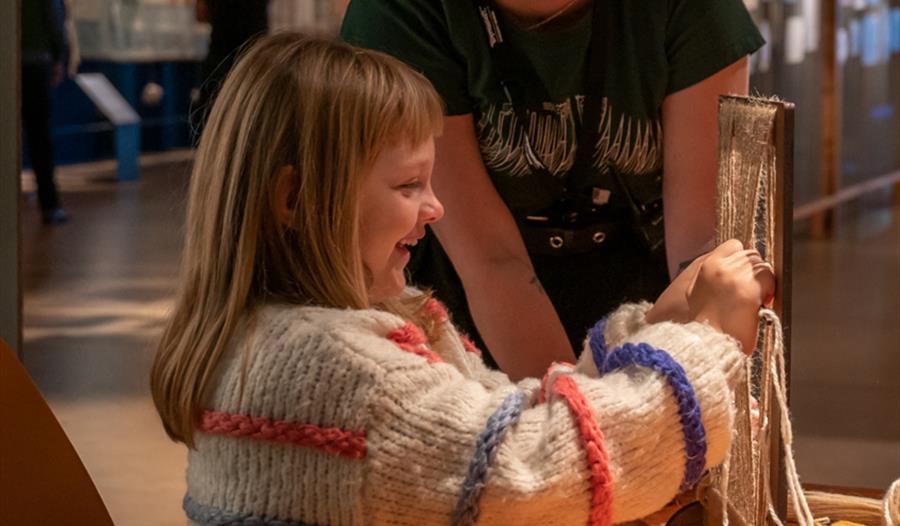 Museumsvert og barn vever