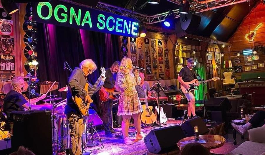 En mann spiller gitar og en kvinne synger på scenen på Ogna Scene