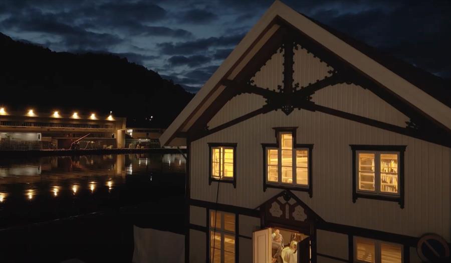 Et hvit trehus med lys bak vinduene