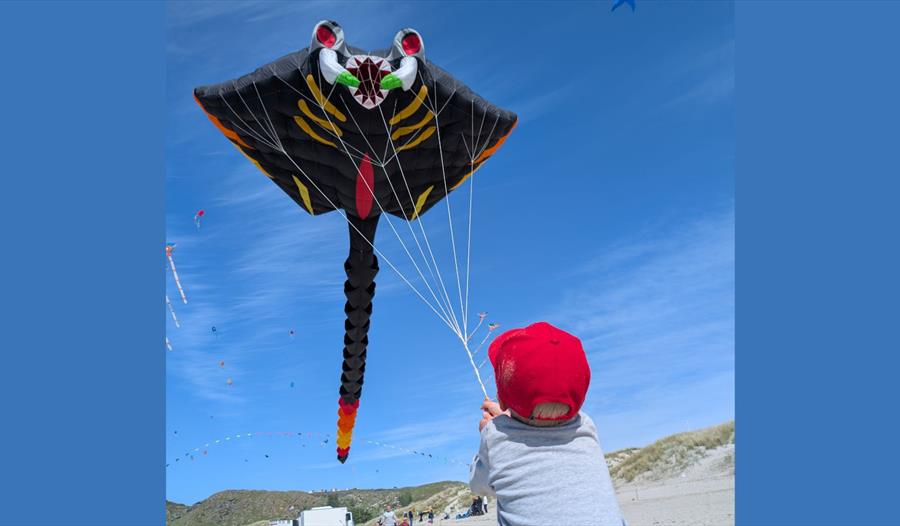 Et barn som flyr en drage på stranden.