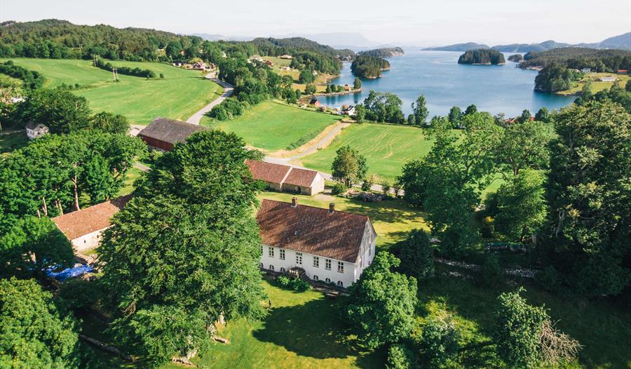 Dronebilete av Halsnøy Kloster med fjorden i bakgrunnen.