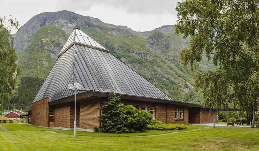Eidfjord nye kirke sett fra utsiden. Den er laget av rød murstein med en trekantet glasstak.