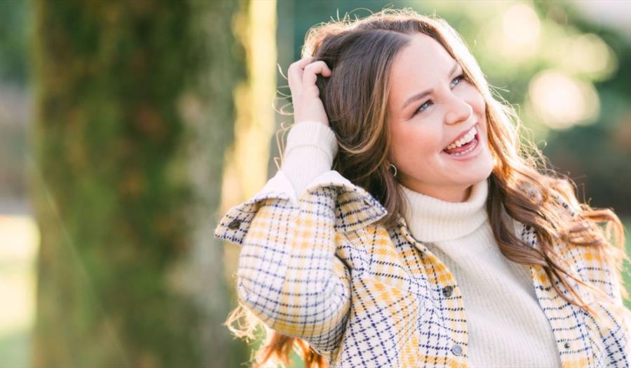 Ei ung dame, Ava Everland som smiler foran et tre.