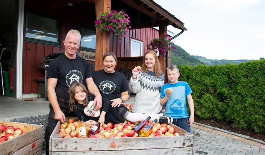 Ein familie nyt haustinga av ferske eple på Spildegarden i Hardanger. Opplev ekte norsk frukttradisjon i hjartet av fjordlandskapet!