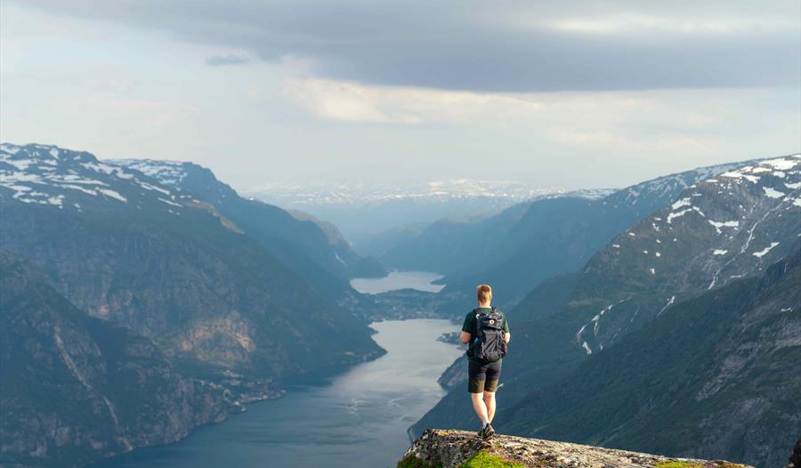 Person står og ser utover naturen, deriblant Folgefonna isbre.