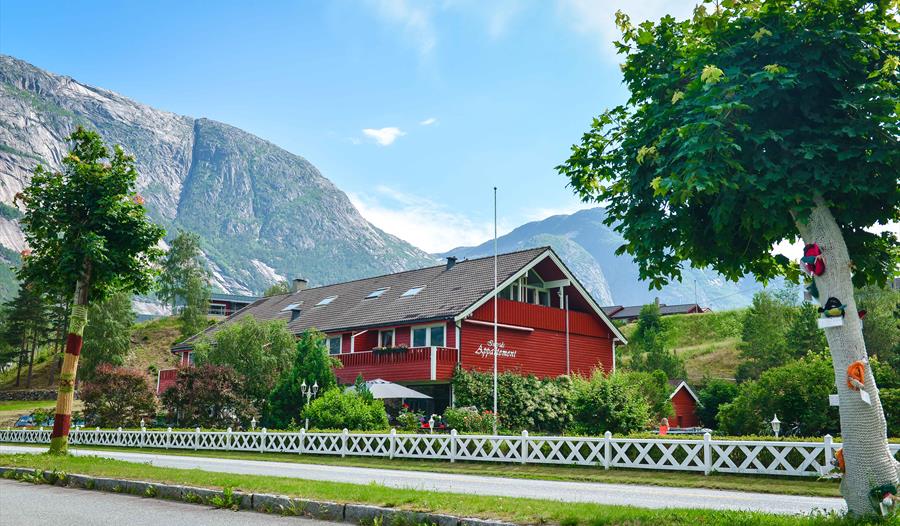 Ingrids Apartments sett fra utsiden, omgitt av grønne trær og med den blå himmel over.