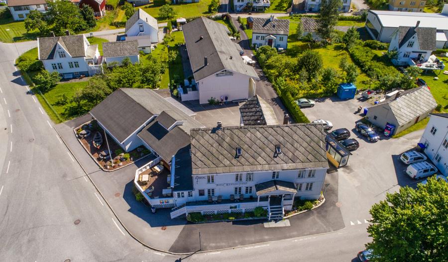 Luftfoto av Jondal Hotel & Gjestgjevarstad, omgitt av grøne hagar og tradisjonelle bygningar i Jondal sentrum, Hardanger.
