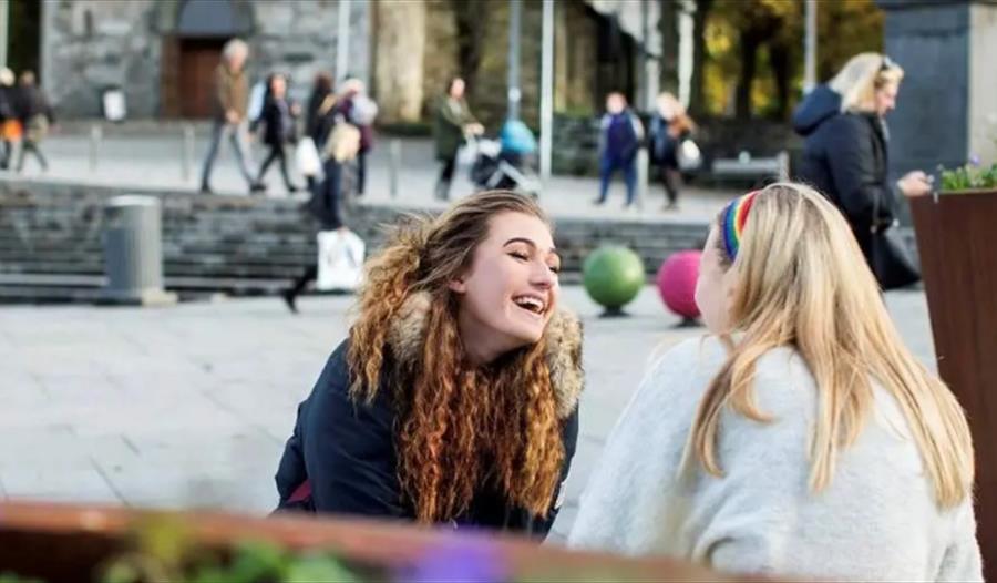 Bilde av to jenter som sitter å ler i Stavanger sentrum