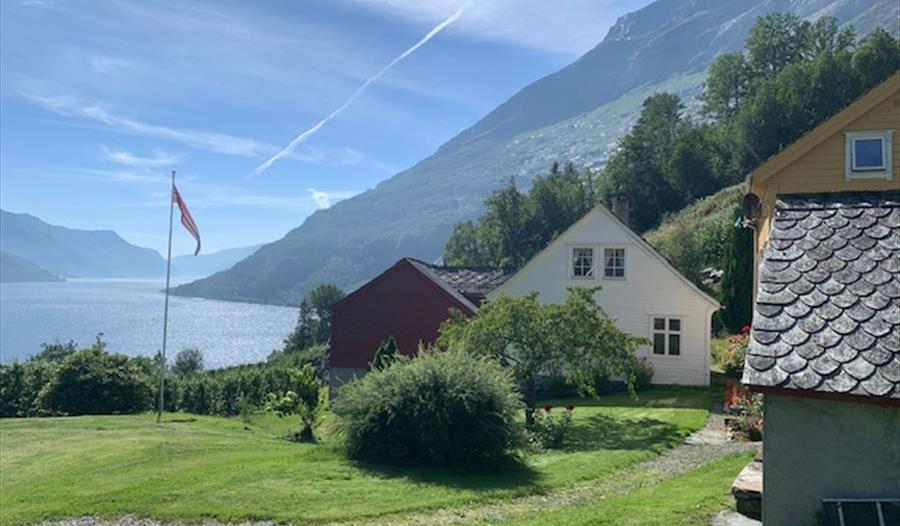 Sjarmerande tun på Jaastad Gjestetun med utsyn til Hardangerfjorden og majestetiske fjell.