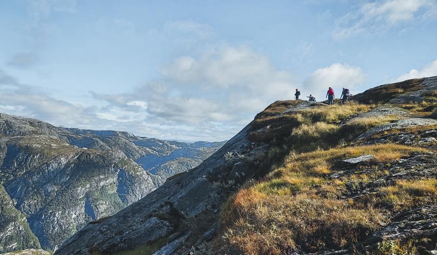Fjellvandrarar på rygg med vid utsikt over fjellandskap i Hardanger, perfekt for fotturar og naturopplevingar