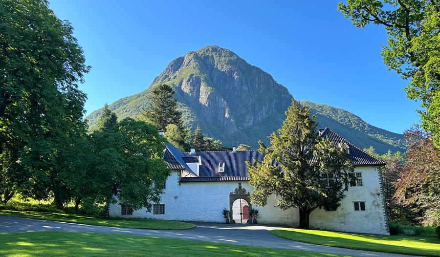 Baroniet Rosendal, omgitt av grøne hagar og mektige fjell i Kvinnherad.
