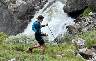 En man på tur i fjellet passerer en foss