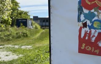 Utsikt fra den åpne døren: grå bygning og en del av plakat  med SOLA skrevet på