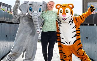 En jente med to artister utkledd som en tiger og en elefant
