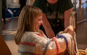 Museumsvert og barn vever